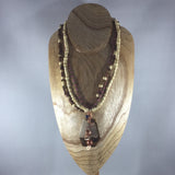 A small present box with a jingle bell inside dangling off a hand beaded rope.  Matching earrings included.  Necklace 16"
