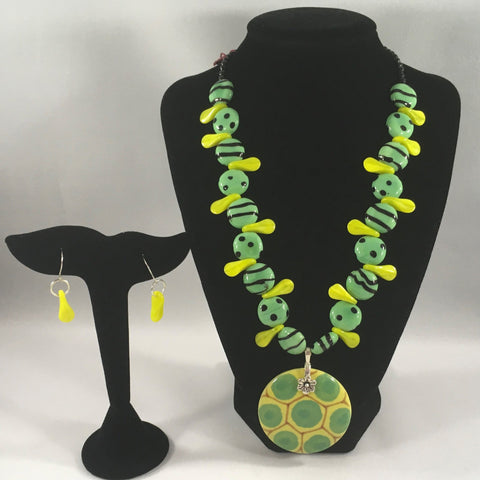 Green striped and spotted ceramic and yellow duckbill beads with pendant.  Necklace measures 18" around.  Pendant 2".  Sterling wire earrings included.