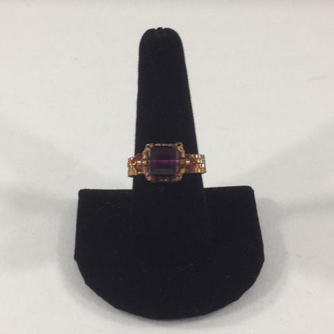 Amethyst Swarovski Cube Ring with 2 topaz accents.  Shimmer Gold Glass Seed Bead Band.  Size 9 1/2.  Although this ring is strung with Fireline, constant water exposure while wearing is not recommended.