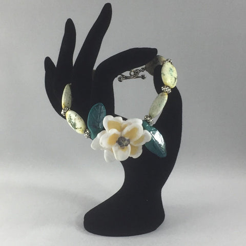 A White and Pale Yellow Flower and Green Leaves made of Porcelain are the centerpiece for this bracelet. The spacers are silver. The clasp is Sterling Silver.  Size 8