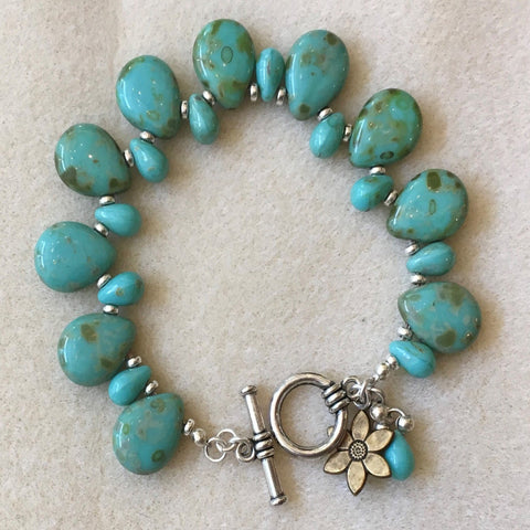 Picasso turquoise teardrop beads and a daisy dangle and sterling spacer beads. Sterling clasp.  Size 7.