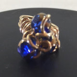 Gold tone Wire Wrap Ring with 3 Blue Cathedral Beads wrapped around swirls of ire.  Size 7 1/4