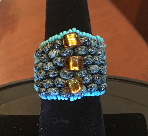 Beaded, Turquoise, Gray mottled and Gold accent Beads.  Size 7.  Although this ring was strung with Fireline, constant exposure to water is not recommended.